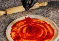 عکس ترفند ریختن سس کچاپ روی خمیر پیتزا قبل از مواد